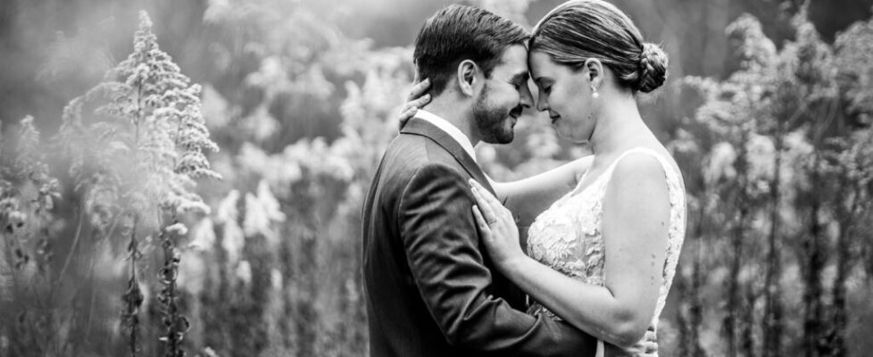A black and white photo of a couple looking at each other with a bokeh effect.